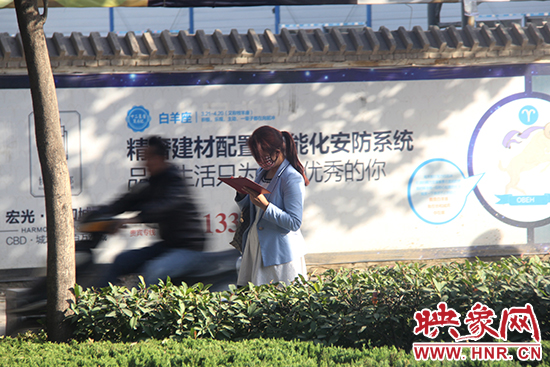 一名女士看著手機走路 一名女士看著手機走路