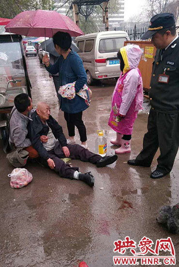 女孩為倒地老人撐傘。