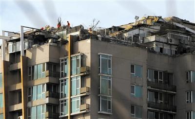 　　昨日，身穿橘黃色馬甲的工作人員在人濟(jì)山莊樓頂拆除違章建筑。新京報(bào)記者 吳江 攝