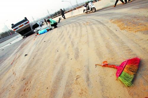 被撞的環(huán)衛(wèi)工躺在地上，身上蓋著藍(lán)色布?jí)K，現(xiàn)場(chǎng)除散落的汽車碎片外，還留有被撞斷的掃帚。