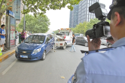 在金水路，交警對(duì)在機(jī)動(dòng)車道違法停放的車輛施行拖離