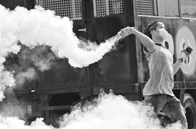 12月2日，泰國(guó)曼谷，一名反政府示威者在總理府附近向負(fù)責(zé)執(zhí)勤的警察投擲催淚彈。英拉請(qǐng)求示威者不要再試圖占領(lǐng)政府工作部門(mén)，不要逼迫政府工作人員選邊站。