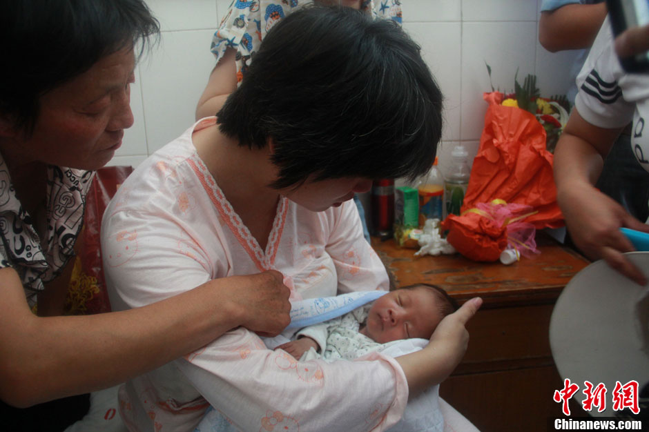 圖為久別重逢，獲救嬰兒母親悉心撫摸愛子。張一辰 攝