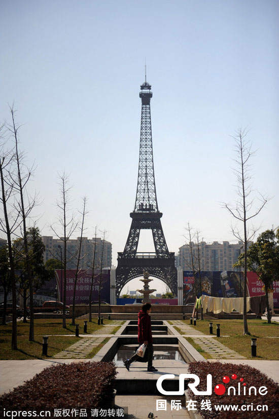 　2014年3月21日，杭州天都城，農(nóng)民在山寨埃菲爾鐵塔下耕作。圖片來源：東方IC