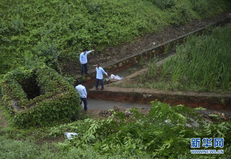5月18日，工作人員在槽罐車泄漏現(xiàn)場附近的水渠邊查看情況。