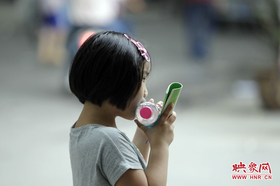 6月7日，鄭州回中考點(diǎn)，一名孩子拿著一瓶礦泉水，等待哥哥走出考場(chǎng)