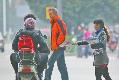 一女子正在路口向行人散發(fā)廣告刊物 一女子正在路口向行人散發(fā)廣告刊物