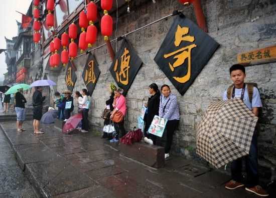 　4月29日上午11時20分，一些游客和古城當(dāng)?shù)氐木用穸阍谝粋€酒吧的屋檐下避雨。這些當(dāng)?shù)鼐用褚詾橛慰团恼罩\生，一場降雨讓他們的生意更加清淡。