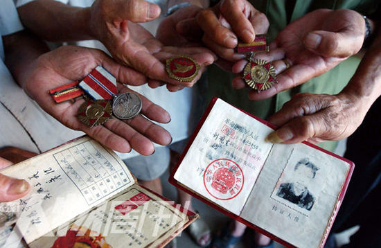 幾位志愿軍老兵展示自己的立功證、傷殘軍人證與勛章