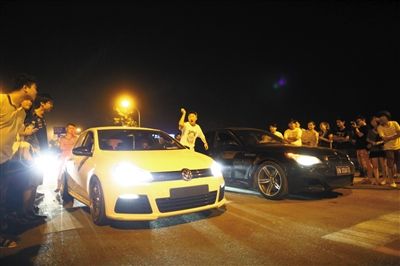 8月24日晚，東壩中街飆車現(xiàn)場，兩輛車并排等待出發(fā)指令，旁邊許多愛好者前來觀看比賽。新京報記者