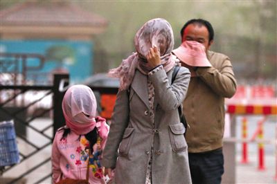 昨日下午，朝陽(yáng)區(qū)豆各莊，行人將紗巾裹在頭上防沙塵。