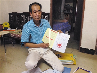 翻出一家網(wǎng)站贈(zèng)予的“中國(guó)好人”證書，區(qū)少坤單膝跪在地上，“你看，我是中國(guó)好人啊?！?范春旭 攝