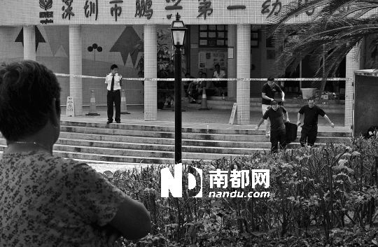 →7月19日，鵬興花園第一幼兒園門前，民警在現(xiàn)場進(jìn)行完勘查取證后，園長和保安的尸體被運(yùn)走。南都記者 徐文閣 攝