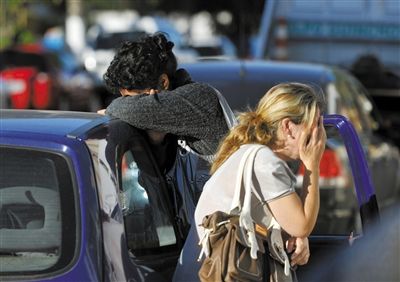 27日，遇難者親友在火災現(xiàn)場旁哭泣。