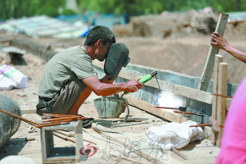 　正午陽光下，工地上的焊接工人還在認(rèn)真工作。