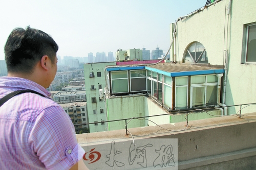 執(zhí)法人員正在對一高層住宅樓頂層加蓋的違章建筑調查取證