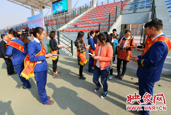 活動現(xiàn)場工作人員給同學們發(fā)放宣傳冊、環(huán)保袋。