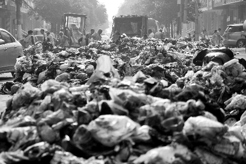 垃圾堆滿整個(gè)路口，環(huán)衛(wèi)工人們正在清理