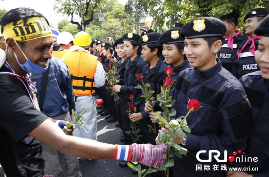 2013年12月03日,曼谷總理府與曼谷警署允許反政府示威民眾進(jìn)入,雙方進(jìn)入暫時“停戰(zhàn)”狀態(tài)迎接泰王生日。曼谷警察總署,女警們手持鮮花送給反政府示威民眾。圖片來源:Manish Swarup/東方IC