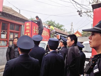 昨日下午,東城區(qū)工商、城管、公安等部門,對雍和宮附近的預測中心進行清理整頓,站在車頂?shù)膬擅と苏鸪患摇邦A測中心”的招牌。因雍和宮、白云觀等文化景點外聚集大量算命先生,被媒體稱為“算命一條街”。本版攝影/新京報記者 李寧 攝