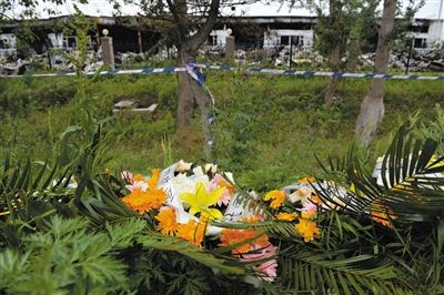 昨日，吉林省德惠市吉林寶源豐禽業(yè)有限公司燃燒事故現(xiàn)場警戒線外，遇難者家屬在路邊擺放了花圈祭奠逝去的親人。吳江 攝