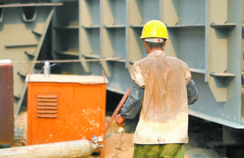 工地上，一建筑工人的衣服被汗水浸透。