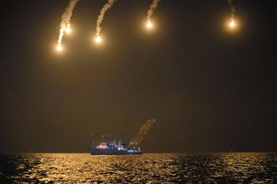 22日，搜救人員在照明彈的光亮下連夜搜救。