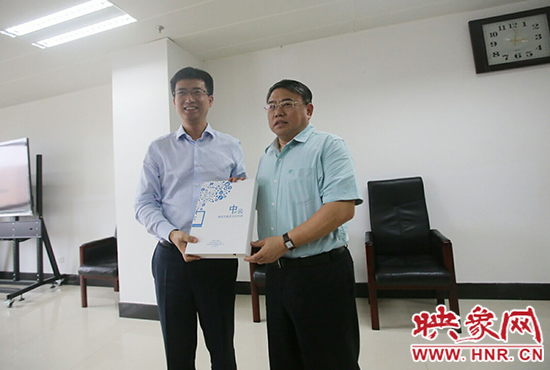 阿里云計算總裁胡曉明向河南省新聞出版廣電局局長朱夏炎遞交《中原云平臺交付手冊》。