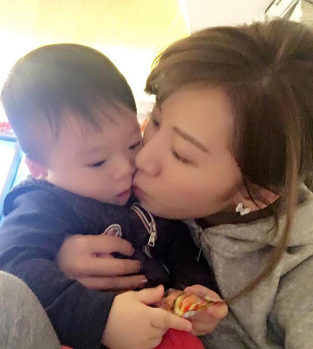 照片中李念狂吻兒子，小寶貝自顧自地玩著。