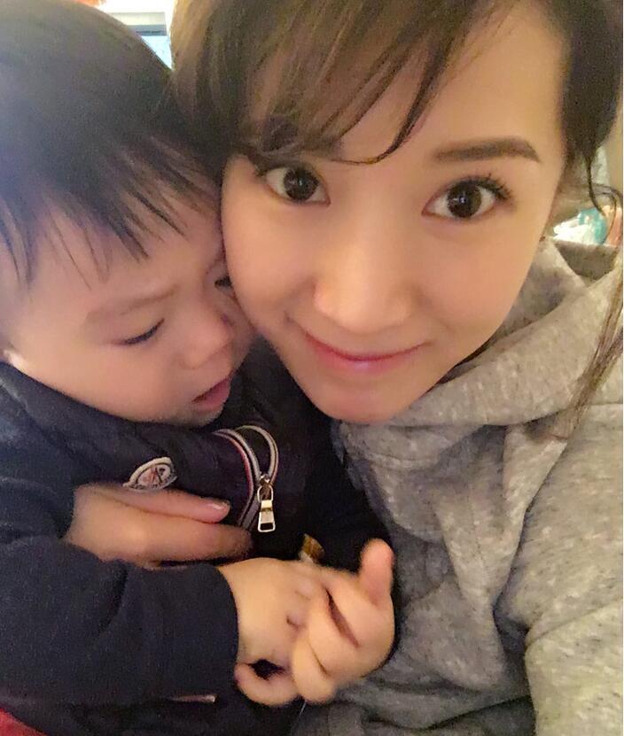 照片中李念狂吻兒子，小寶貝自顧自地玩著。