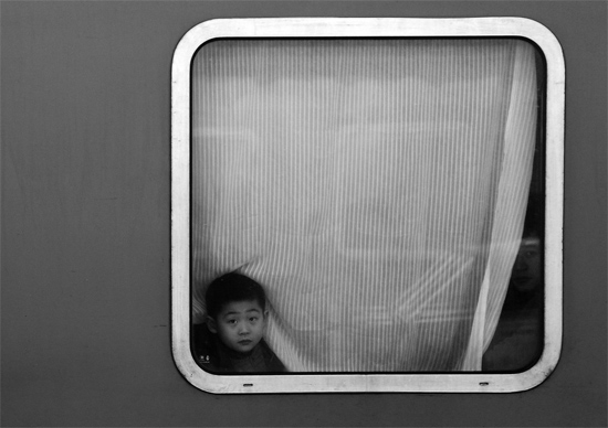 一個(gè)孩子把頭伸向窗外，他想再看送別的親人一眼