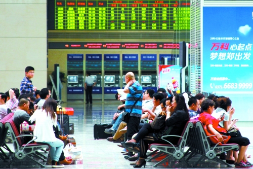 候車大廳溫度很高，一名乘客一手扇風(fēng)、一手擦汗