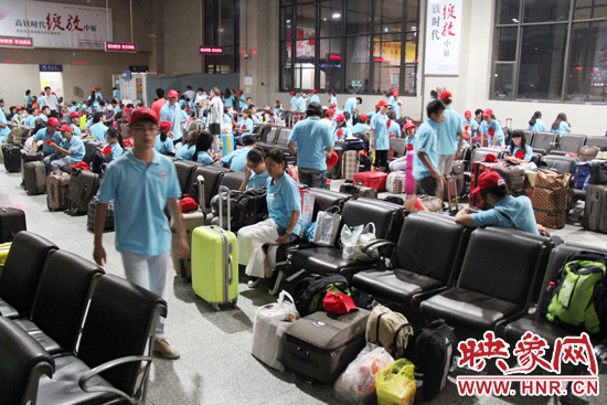 大學(xué)生志愿者在火車站候車室內(nèi)整裝待發(fā)。