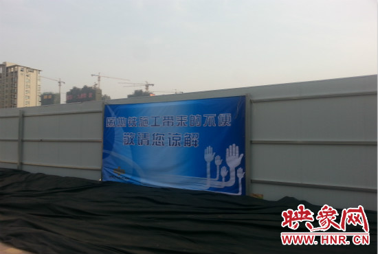 道路南側(cè)圍起了白色的圍擋，墻上標(biāo)示著“因地鐵施工帶來的不便敬請(qǐng)您諒解”的提示牌。