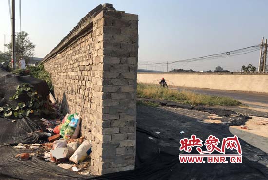 一墻之隔，一邊是道路，一邊是垃圾和荒草，市民質(zhì)疑其為遮羞墻。