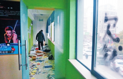 　健身會所地上一片狼藉，玻璃上噴著黑色“欠錢”二字。