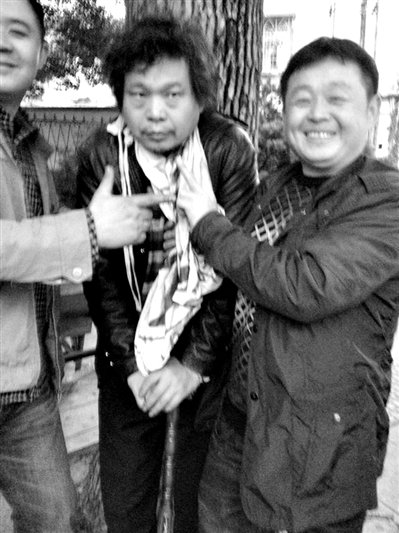 兩名接訪人員與患有癌癥的訪民段新德合影時，面帶笑容擺出勝利的手勢。