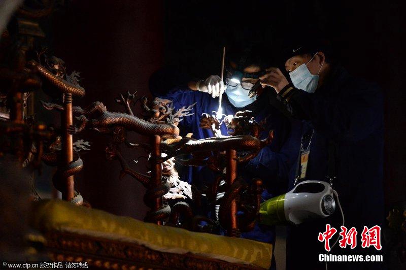 圖為工作人員使用軟毛刷和吸塵器對太和殿的金漆雕龍寶座除塵。
