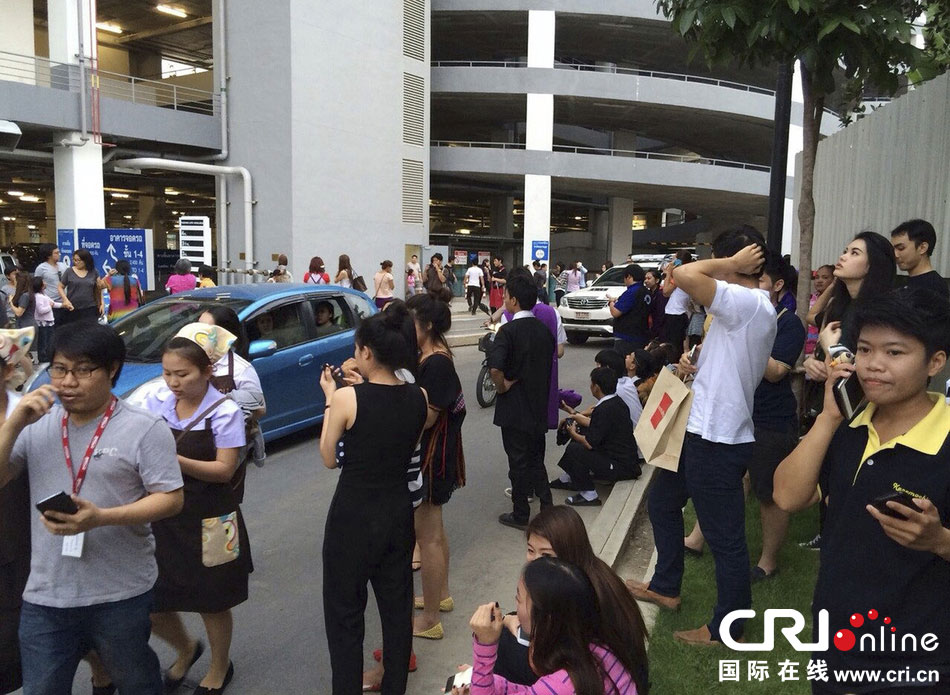 當?shù)貢r間2014年5月5日，泰國清萊，工人們站在一棟大樓外避難。