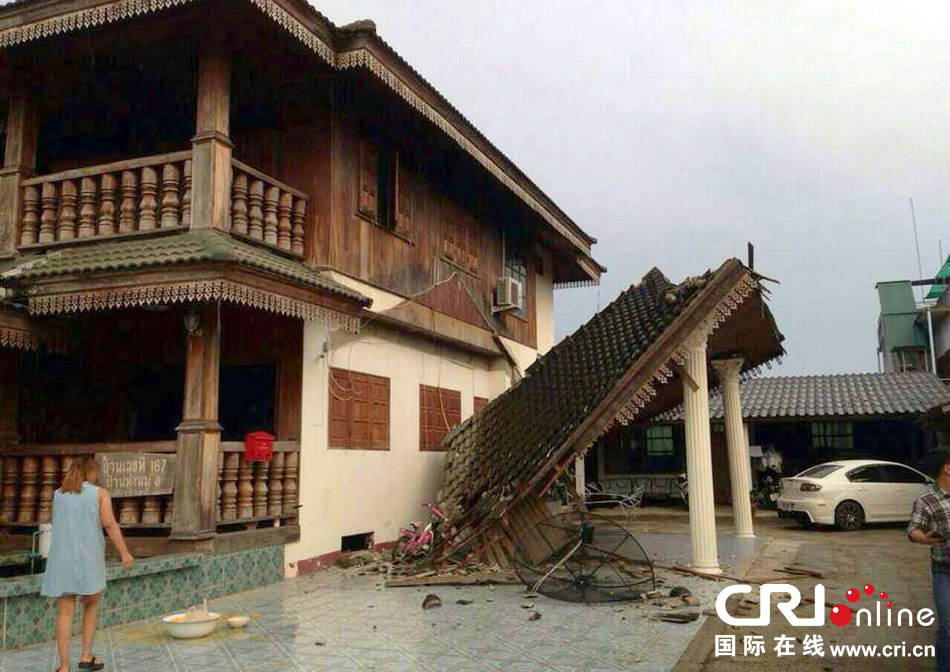 當?shù)貢r間2014年5月5日，泰國清萊，一名婦女看著受損的房屋。 圖片來源：東方IC