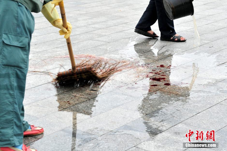 圖為環(huán)衛(wèi)工人在清理案發(fā)地點的血跡。