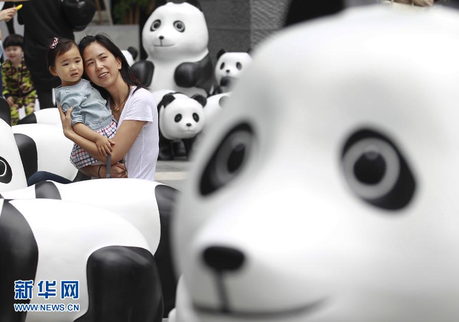 6月2日，一位家長帶著孩子在上海街頭和大熊貓模型合影。