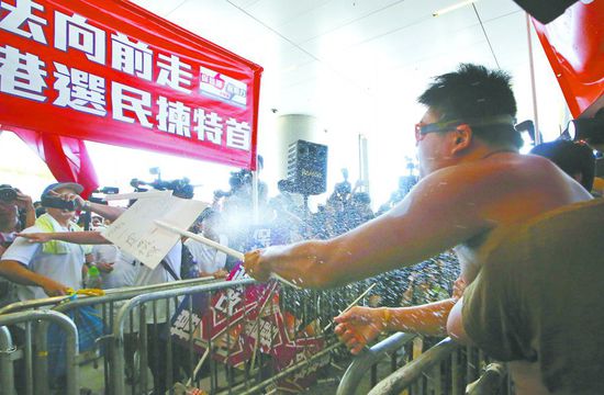 17日，在香港立法會(huì)外，一名反對(duì)政改的男子向支持派人群投擲標(biāo)牌。