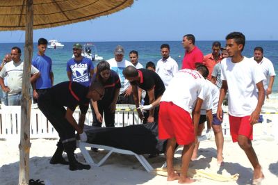 6月26日，在突尼斯蘇塞，救生員和醫(yī)務(wù)人員在發(fā)生襲擊事件的海灘運送一名死者的遺體。新華社發(fā)