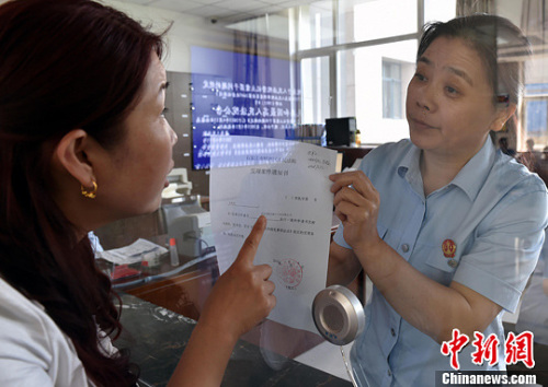 資料圖：2015年5月4日，河北石家莊市橋西區(qū)人民法院立案庭庭長齊燕正在為立案人辦理相關手續(xù)，完成整個過程只用了5分鐘。當日是立案登記制改革首個工作日，該院共立案36件，立案率達到90%。中新社發(fā) 翟羽佳 攝