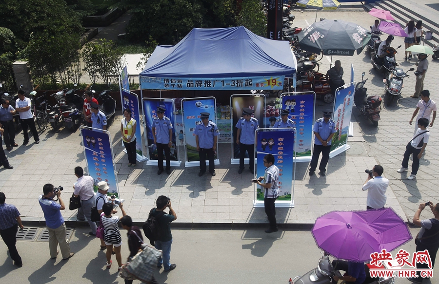 執(zhí)法人員用宣傳牌圍擋占道經(jīng)營(yíng)攤位。