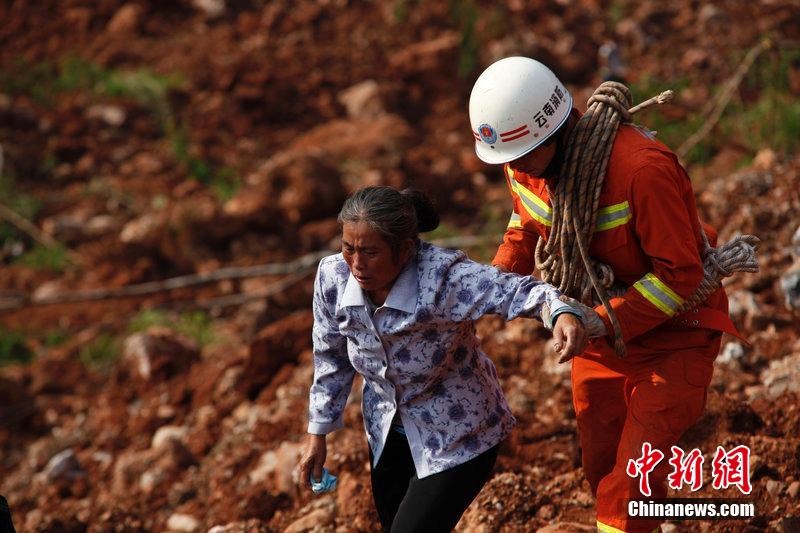 一位消防戰(zhàn)士將一位失去親人的老人扶離滑坡點。