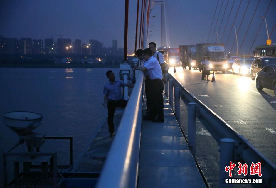 圖為武漢警方談判專家正在與翻爬至大橋外側(cè)護(hù)欄的劫持者談判。