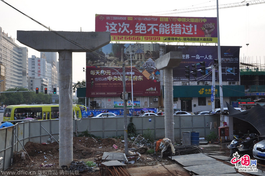 過街天橋一側(cè)的橋樁早已打好,可是對面的郵政銀行網(wǎng)點依舊在照常營業(yè)。