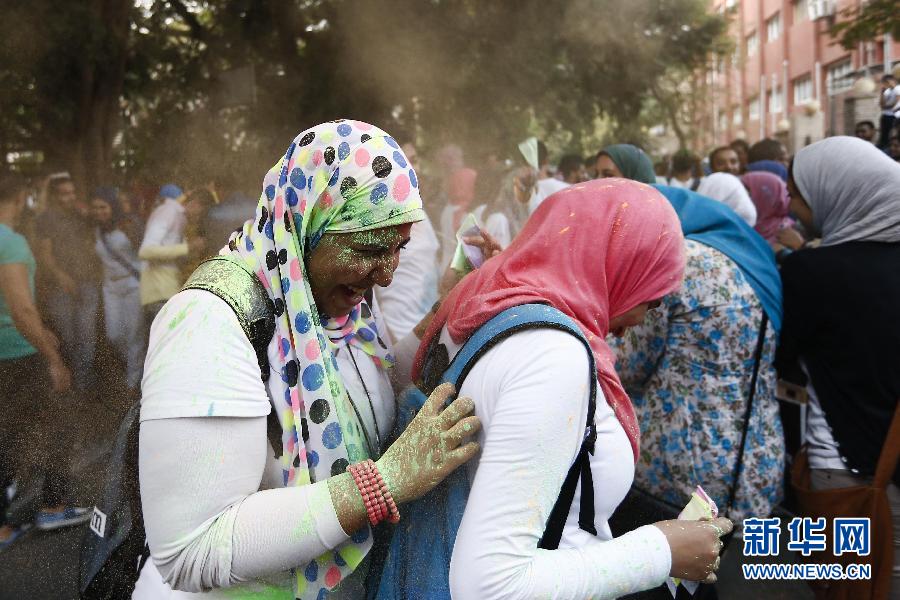 10月16日，在埃及首都開羅，兩名女青年在“彩色跑”活動(dòng)中躲避人們拋撒的彩色粉末。